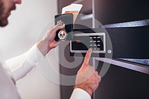 Men`s hand opens a safe hidden in the wardrobe.