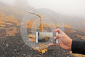 Men`s Hand Photographs on the Smartphone Saxophone. Golden Alto