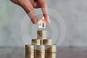 Men`s hand is planning savings money of coins to buy a home, concept for property ladder, mortgage and real estate investment.