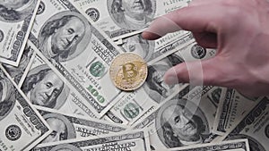 Men`s hand puts a gold bitcoin coin on us 100 dollar. Worldwide virtual internet cryptocurrency and digital payment