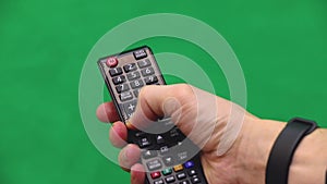 Men`s hand. Remote control. Right hand. Green screen. Press the button.