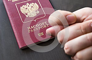 Men`s Hand shows the fico on red passport backgound. Symbol of sanctions. Negative concept. Closeup