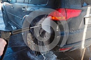 Men's hand wash dirty SUV by high pressure wash. Touchless car wash self-service in the open air. Contactless car wash self-servi