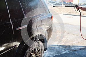 Men's hand wash dirty SUV by high pressure wash. Touchless car wash self-service in the open air. Contactless car wash self-servi