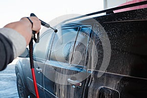 Men's hand wash dirty SUV by high pressure wash. Touchless car wash self-service in the open air. Contactless car wash self-servi