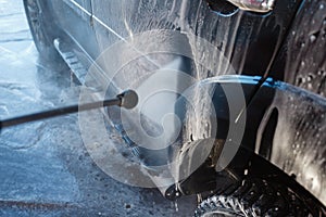 Men's hand wash dirty SUV by high pressure wash. Touchless car wash self-service in the open air. Contactless car wash self-servi