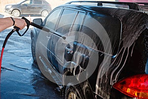 Men's hand wash dirty SUV by high pressure wash. Touchless car wash self-service in the open air. Contactless car wash self-servi
