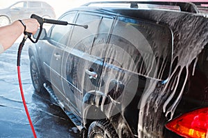 Men's hand wash dirty SUV by high pressure wash. Touchless car wash self-service in the open air. Contactless car wash self-servi