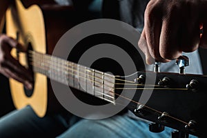 Men`s hands adjust the acoustic guitar