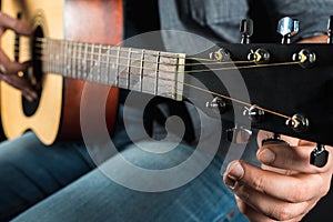 Men`s hands adjust the acoustic guitar