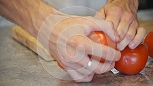 Men's hands beautifully spread tomatoes on a wooden cutting board. Work as a food stylist and blogger.