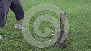 Men's hands chop firewood with an ax on a special stump on the background of beautiful green grass