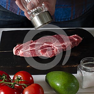 Men& x27;s hands cook a meat steak that lies on a cutting board