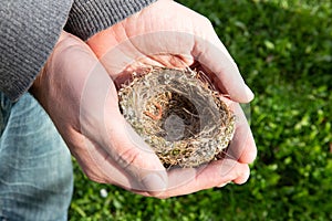 Men`s hands delicately holding an empty bird`s nest. Farm life, italian countryside