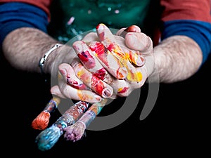 Men`s hands dirty from the paint with paint brushes