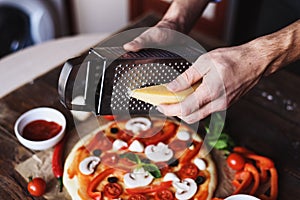 Men`s hands grate cheese for pizza, close up