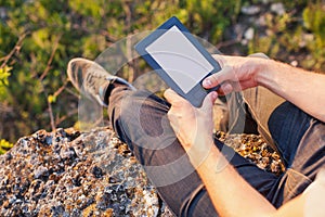 Men's hands hold an eBook on the edge of cliff