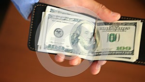 Men`s hands hold a money clip with dollars