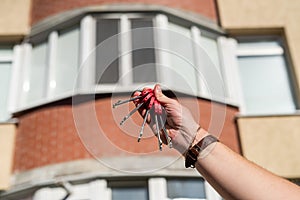 Men& x27;s hands holding key with a keychain in shape of a house on background of cool house.