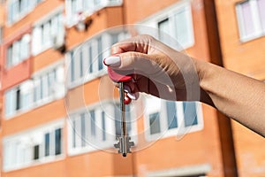 Men& x27;s hands holding key with a keychain in shape of a house on background of cool house.