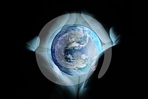 Men`s hands holding the planet earth with a blue glow on a black background.