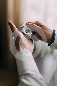 Men`s hands holding and winding up mechanical watch