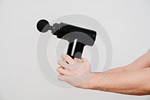 Men`s hands holds a massage gun. medical-sports device