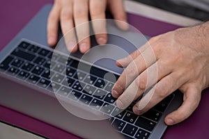 Men`s hands on the keyboard and touchpad laptop