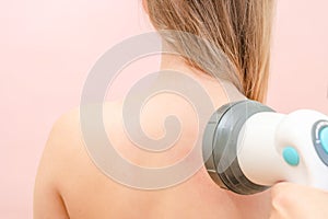 Men's hands massage females neck and shoulder by massager