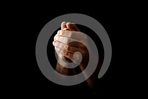 Men`s hands in prayer on a black background. The concept of faith, prayer, mourning, forgiveness, confession