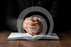 Men`s hands in prayer on a black background. The concept of faith, prayer, mourning, forgiveness, confession