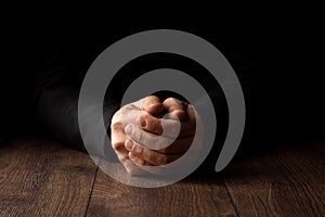 Men`s hands in prayer on a black background. The concept of faith, prayer, mourning, forgiveness, confession