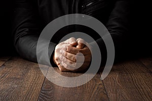 Men`s hands in prayer on a black background. The concept of faith, prayer, mourning, forgiveness, confession