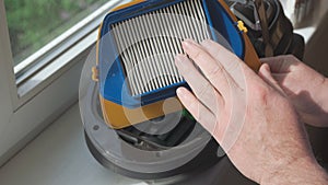 Men`s hands remove dirty filter from vacuum cleaner