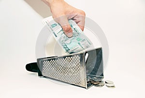 men`s hands rub a banknote on a grater, and coins lie below