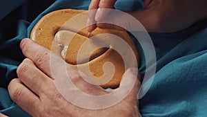 Men's hands scratch sugar cookies candy in the shape of a heart.