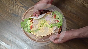 men's hands swerve pita with vegetables and cheese. vegetarian roll.