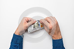 Men& x27;s hands are tearing money. Hands tearing a hundred dollar bill on a white background