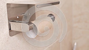 men's hands unwind and tear off a toilet paper. an empty roll remains.
