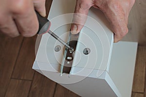 Men's hands use a screwdriver to tighten the screws on the box.