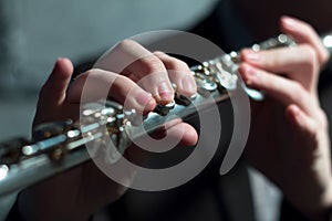 Men`s hands on a wind musical instrument. Playing the flute. Shallow depth of field. Music and sound. Modeling light.