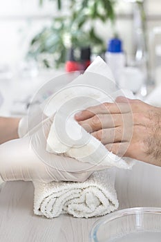 Men`s hands wiped with a towel by the beautician`s hands during a manicure treatment. A man in a beauty salon.