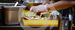 Men`s hands wrapping traditional shawarma wrap with chicken and vegetables