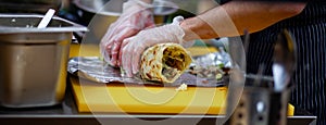 Men`s hands wrapping traditional shawarma wrap with chicken and vegetables