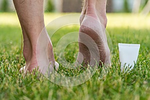 Men\'s heels (feet) with dry skin and scaly with cream on grass