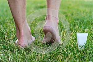 Men's heels (feet) with dry skin and scaly with cream on grass