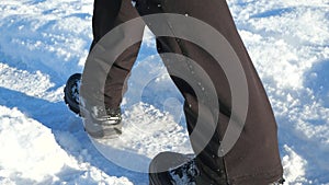 Men`s high waterproof boot in the snow in winter. Boy wear softshell trousers in dark grain color. Walking in snowdrift