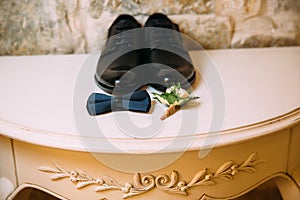 Men`s leather shoes, bow tie and boutonniere on a white table background. Clothing accessories businessman.