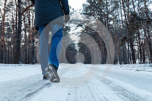 Men`s legs in boots close up the snow-covered path in the winter forest