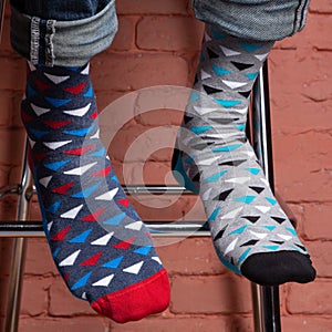 On men`s legs different colored socks, on a background of a brick wall, concept